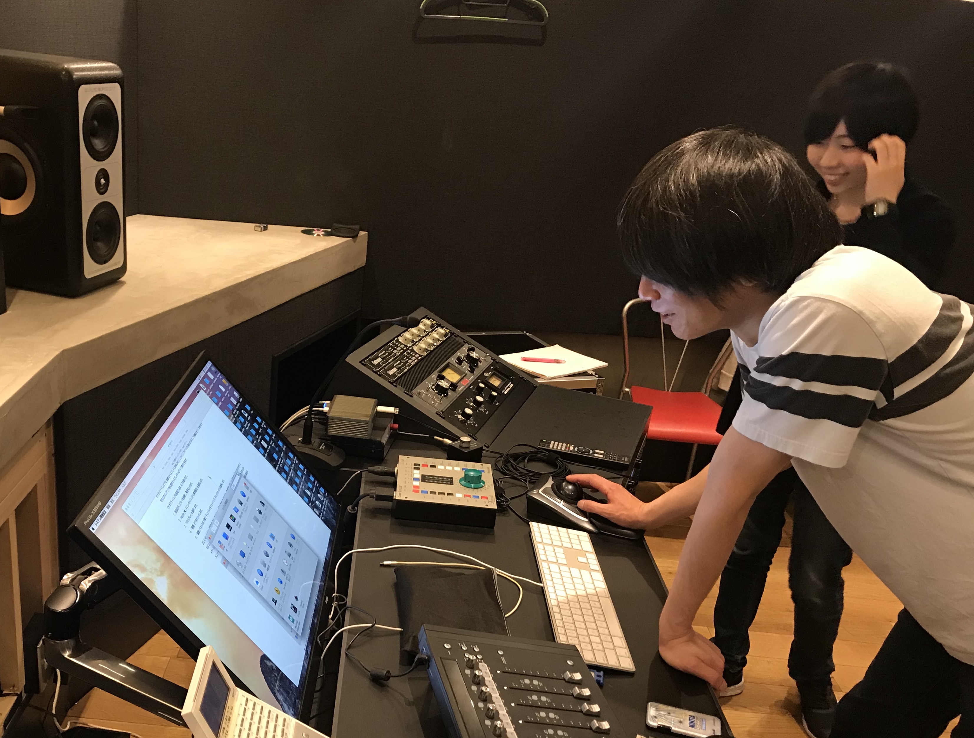 国立音楽院レコーディングスタジオでパソコンを操作する吉崎拓郎講師と音響デザイン科の学生を横から撮影した写真。