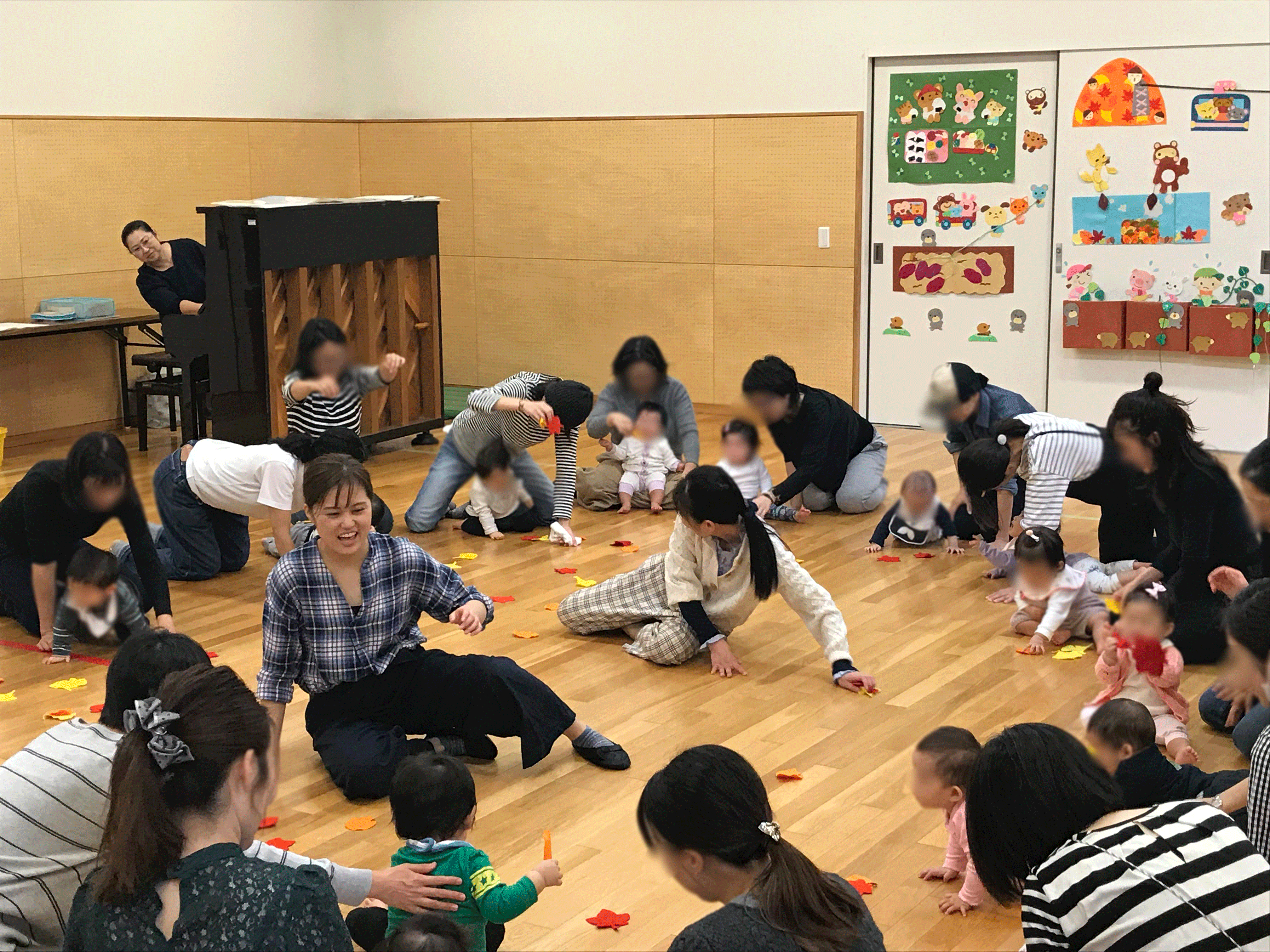 落ち葉を模した小道具を用いた、動きのあるプログラム。輪の中心には小暮先生と共に笑顔で子どもと向き合う実習生の姿。