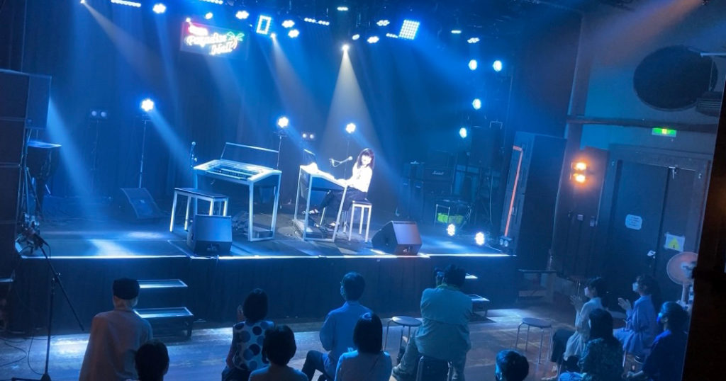 ステージと客席を含む全体が青く照らされたライブ会場
